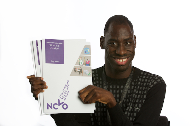 Image shows a close-up of a smiling Michael Hagan, one of The Advocacy Project trustees, holding the four easy read booklets of NCVO The Good Trustees Guide