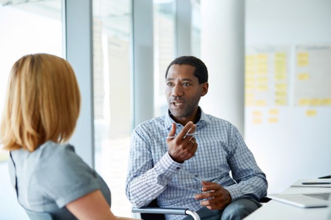 Image shows Shot of two colleagues talking together in a modern office.