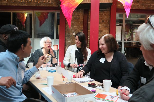 Image shows staff smiling around a table at our staff conference